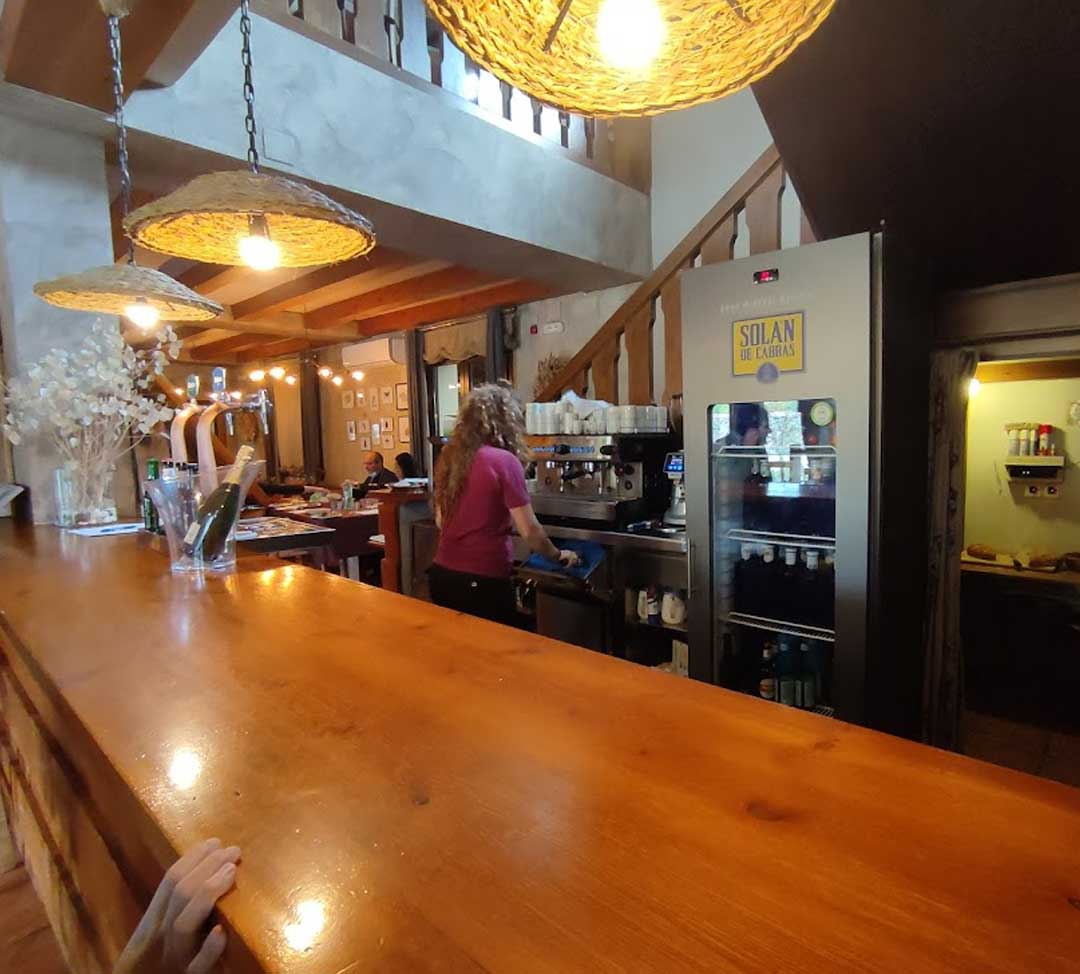 Una mujer está detrás de un mostrador de madera en un restaurante.