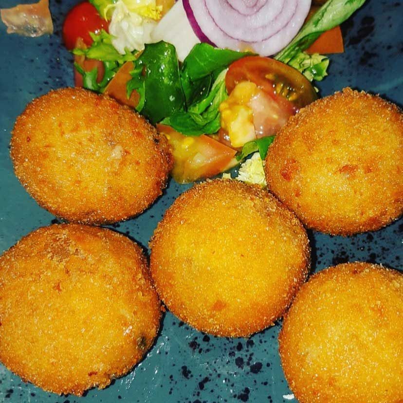 Un plato de comida frita con una ensalada al fondo.