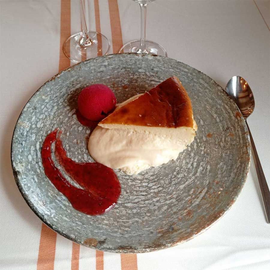 Un plato de comida con un trozo de tarta de queso encima.