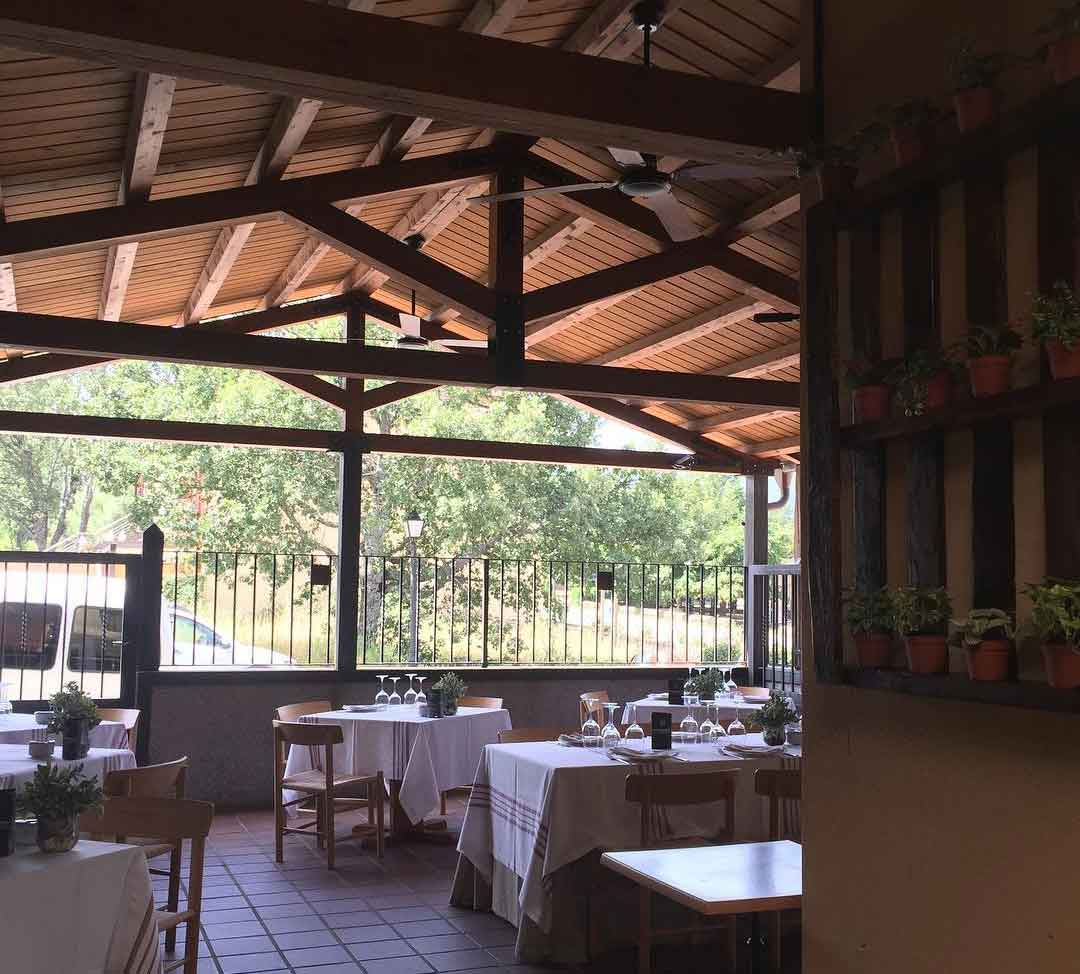 Un restaurante con mesas y sillas bajo un techo de madera.
