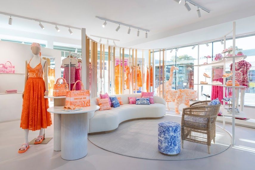 Boutique lumineuse proposant des vêtements, des présentoirs et des sièges orange et roses