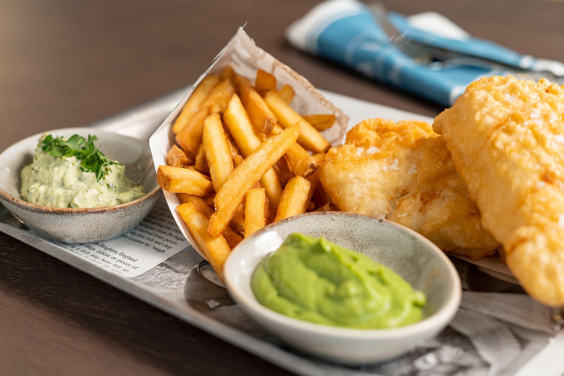 Auf einem Holztisch stand ein Tablett mit Fish and Chips, dazu Remoulade und eine kleine Schüssel mit Erbsenpüree.