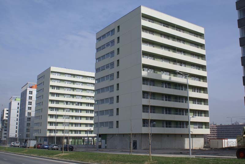 Una hilera de edificios de apartamentos con coches aparcados delante de ellos.