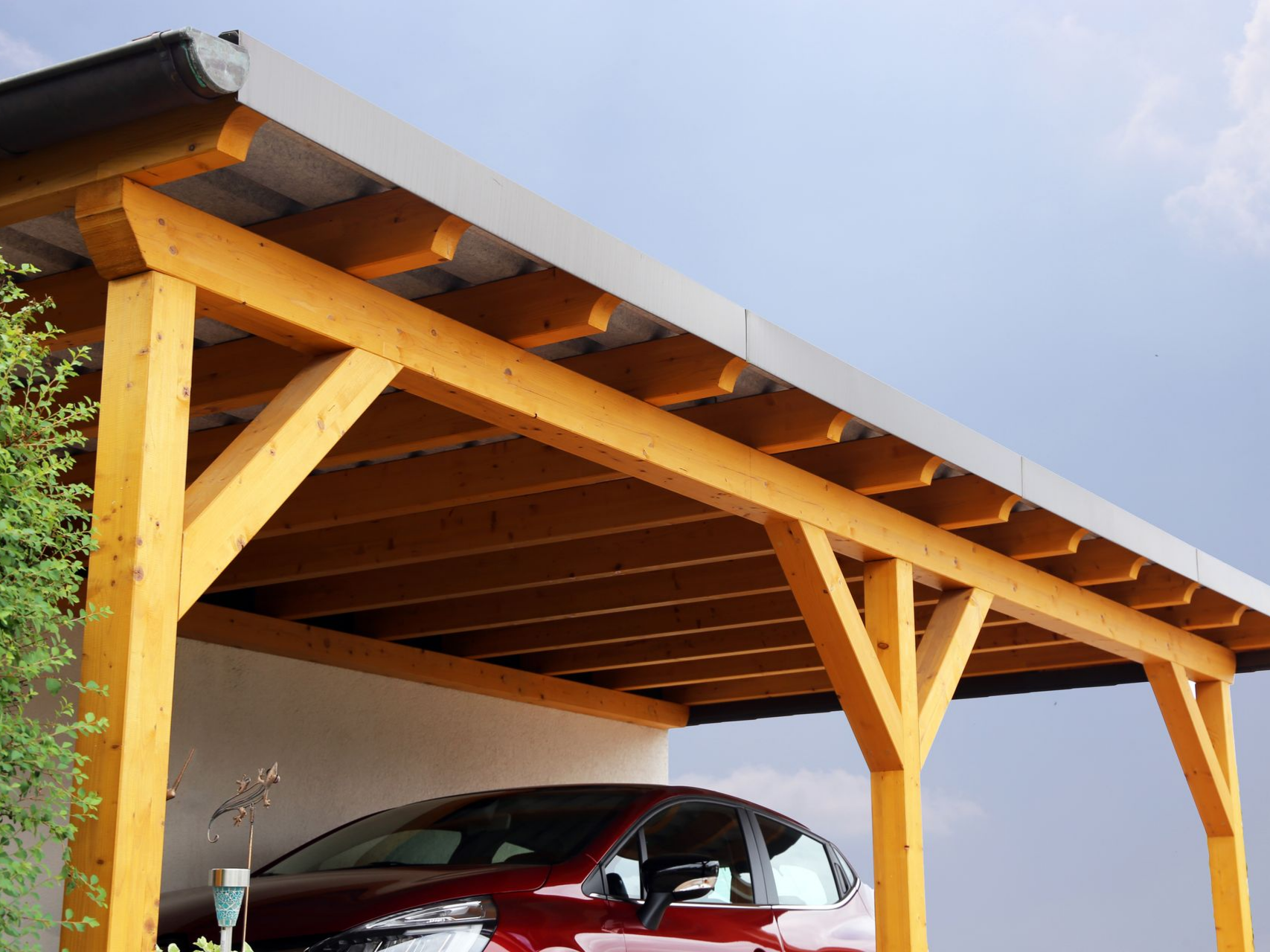 Un abri en bois moderne, devant un mur blanc et un ciel bleu.