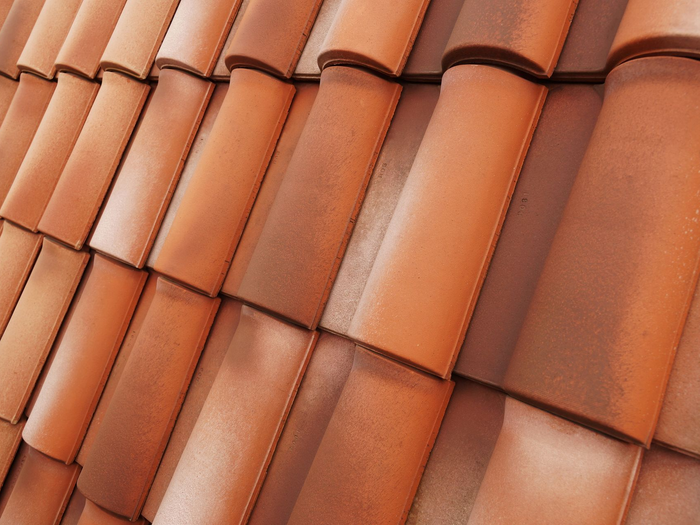 Gros plan sur des tuiles de toit en terre cuite se chevauchant.