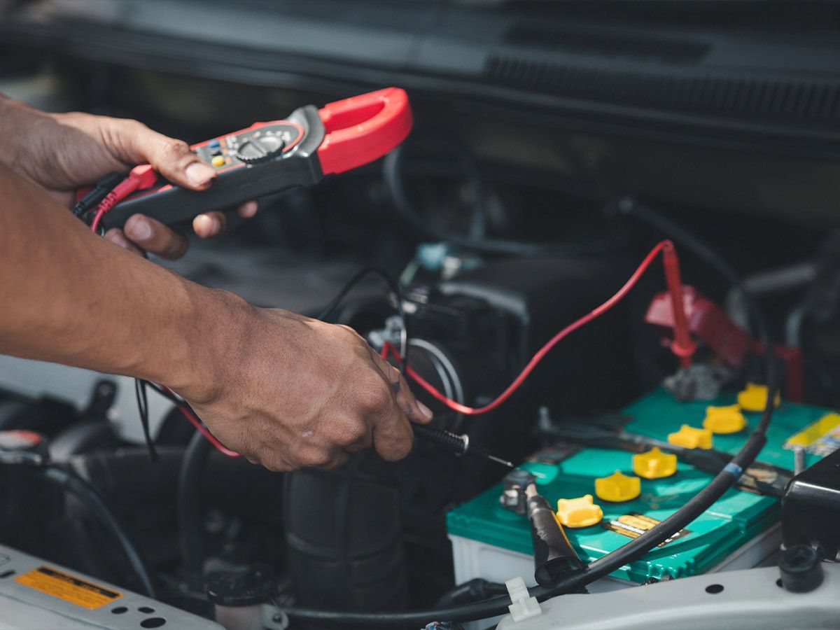 Un hombre está usando una pinza para probar una batería de automóvil.