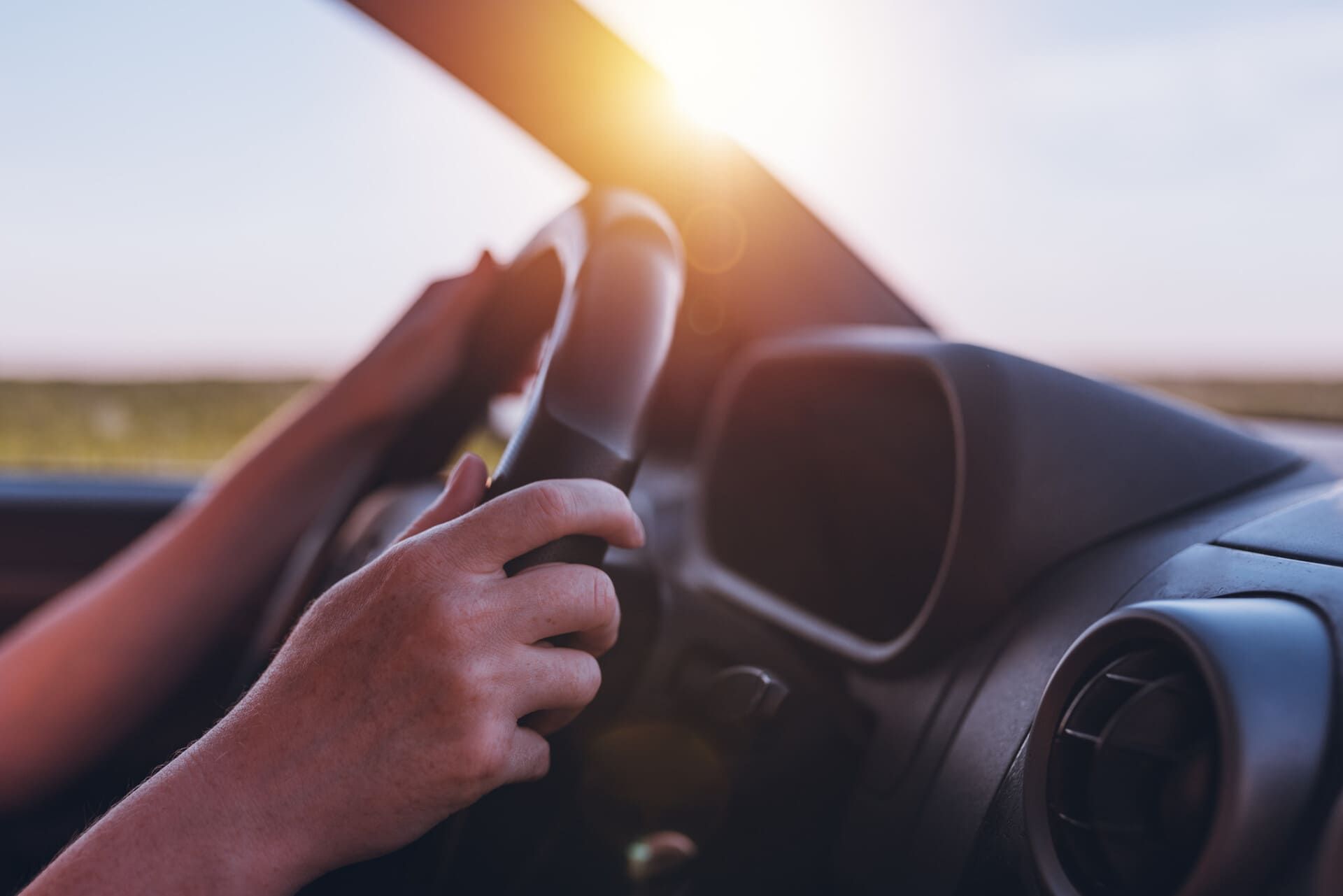 Una persona conduce un coche con las manos en el volante.