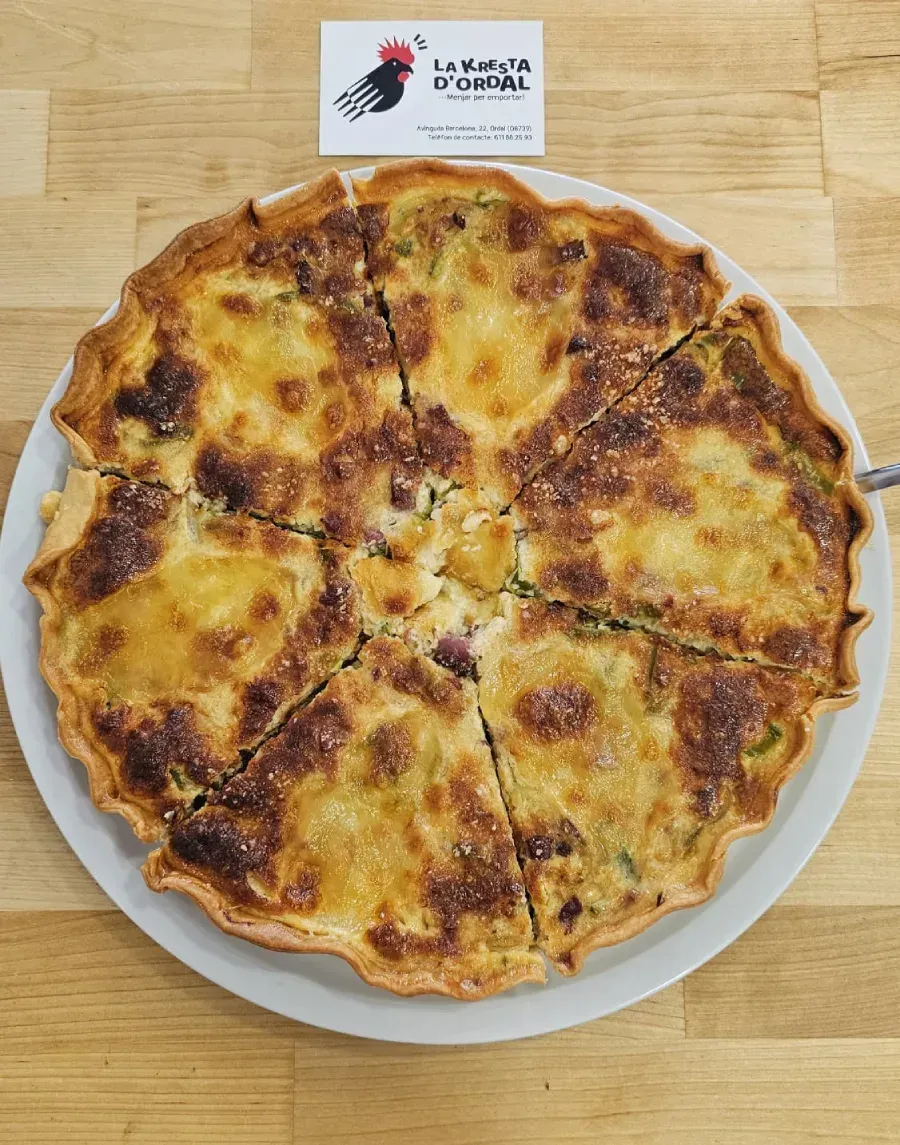 Hamburguesa con huevo frito y tocino en un pan, servida en un plato verde y marrón sobre una superficie de madera.