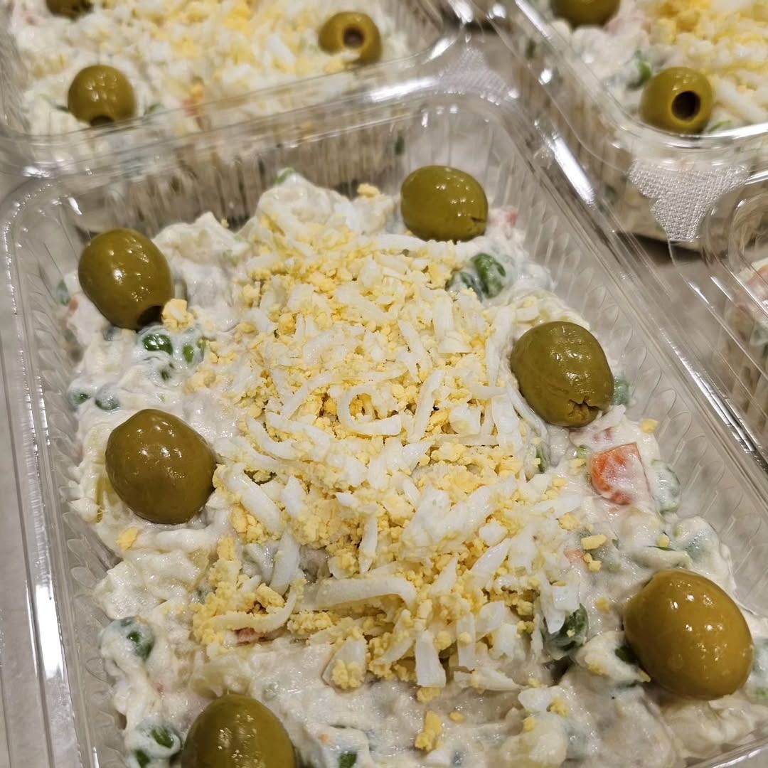 Envases de ensalada de patatas aderezadas con aceitunas y huevo rallado.