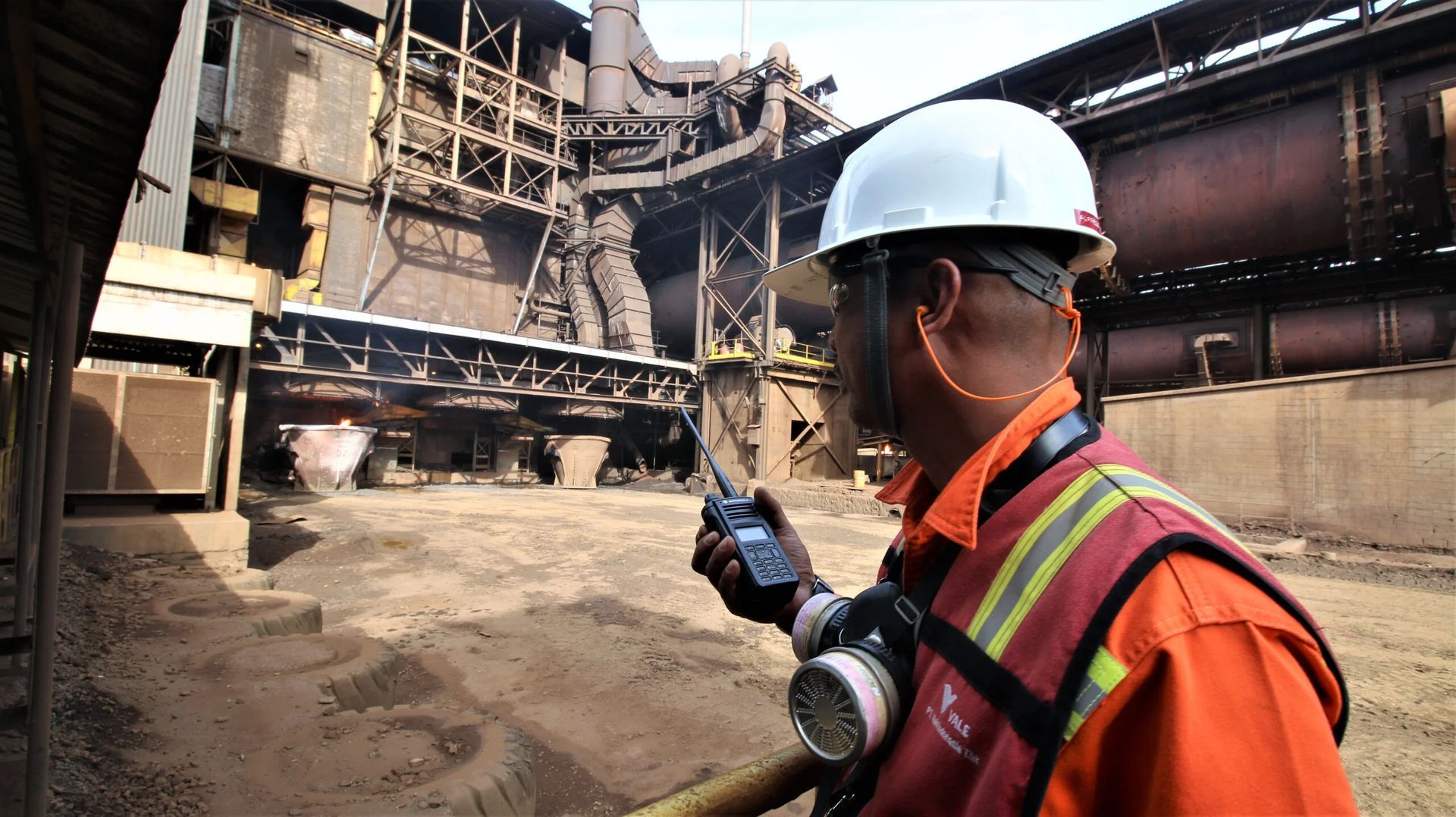 A man wearing a hard hat is talking on a walkie talkie