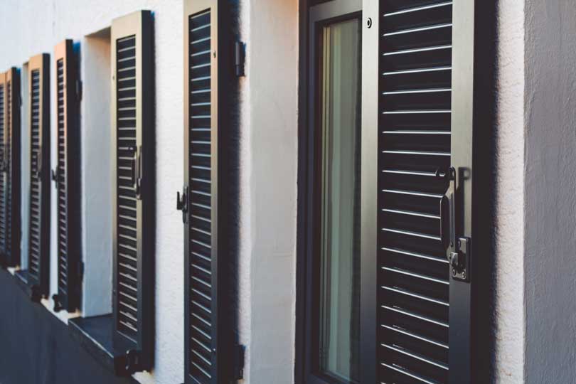 Trois fenêtres avec des volets noirs en aluminium