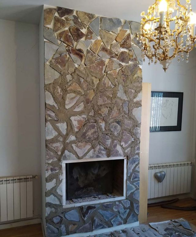 Una sala de estar con una chimenea de piedra y una lámpara de araña.