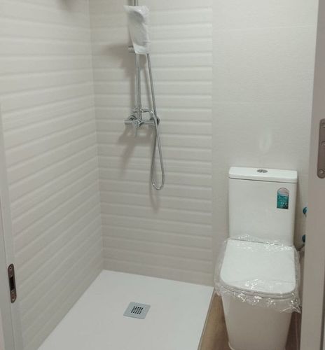 Un baño con inodoro, ducha y cabezal de ducha.