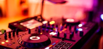 Installation d'une platine et d'une table de mixage DJ sous un éclairage de club rose et violet