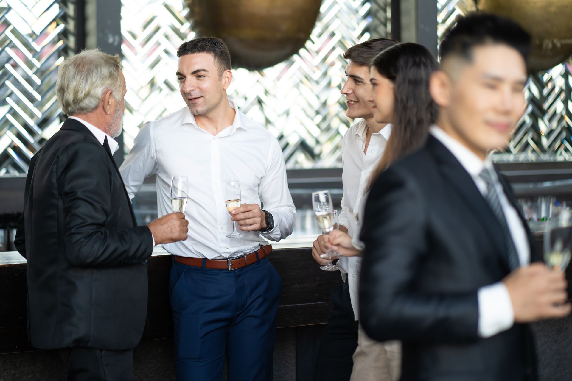 Des personnes en tenue de travail discutent et échangent des idées lors d'un événement social, un verre à la main.