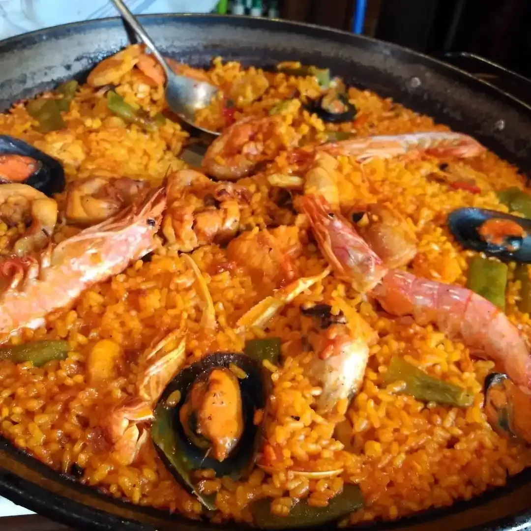 Paella de marisco: gambas, mejillones, arroz y verduras en una sartén grande.