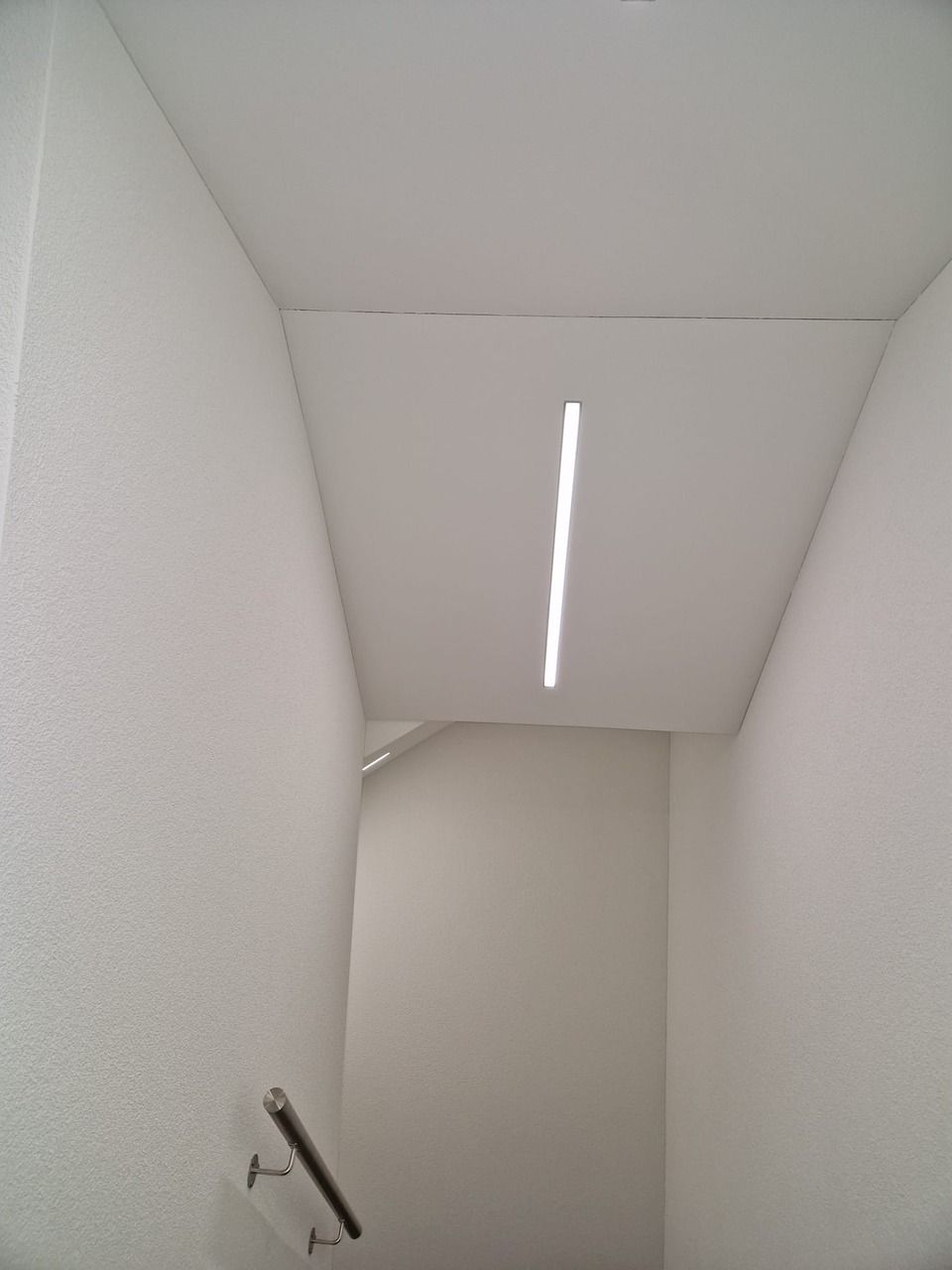 Eine weisse Wand mit einem Licht an der Decke. Foto von der Vini-Bau GmbH.