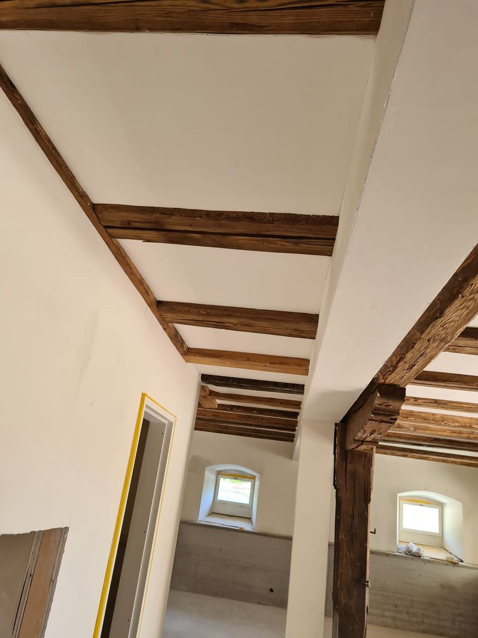 Ein Flur mit Holzbalken und weisser Decke. Foto von der Vini-Bau GmbH.