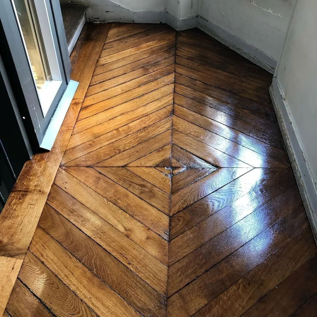 Un fauteuil lounge en cuir noir dans une pièce lumineuse et ensoleillée, avec parquet et hautes portes-fenêtres blanches.