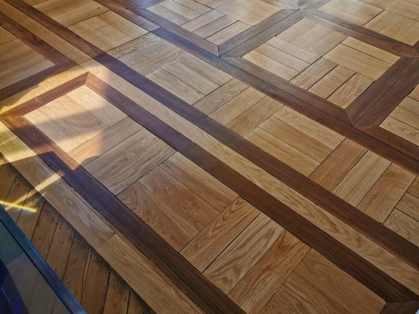 Vue en plongée d'un parquet décoratif en bois présentant des lames de chêne clair.