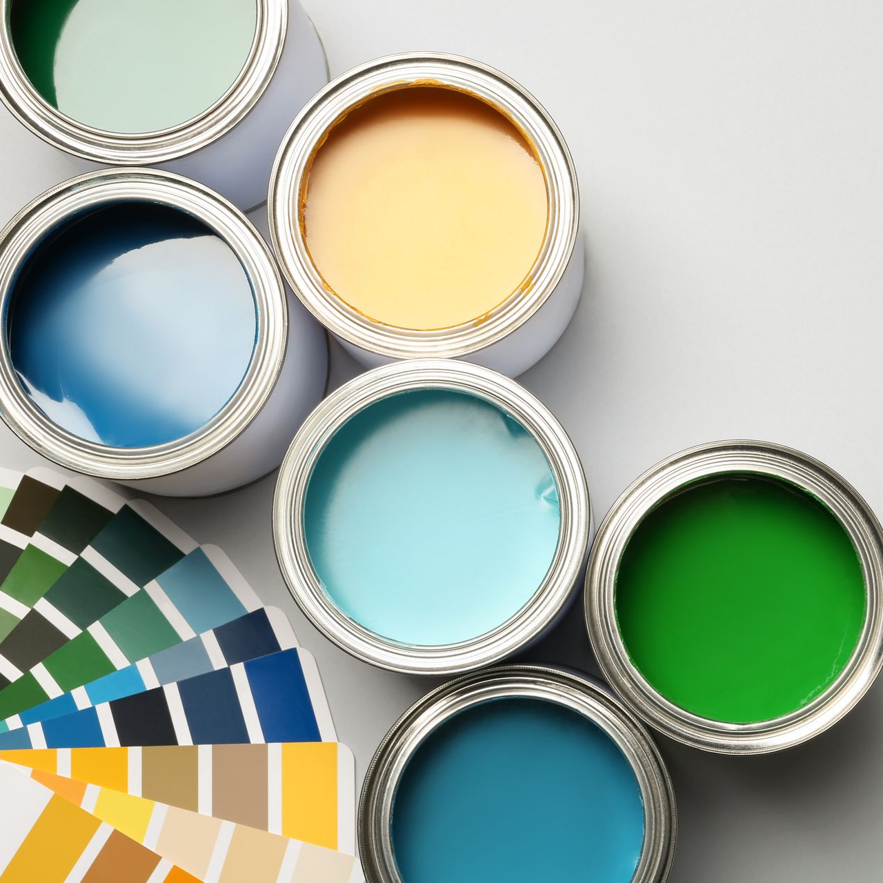 Six pots de peinture ouverts sont disposés à côté d'un éventail d'échantillons de peinture.