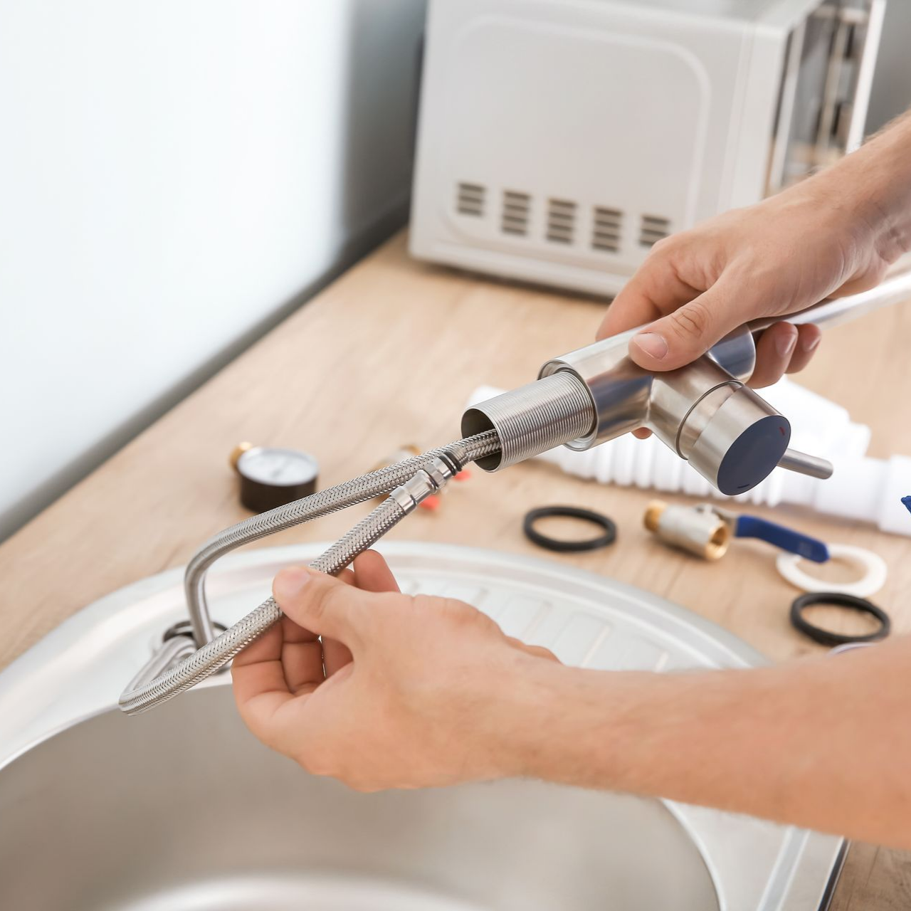 Main qui tient un flexible de plomberie pour installer un robinet