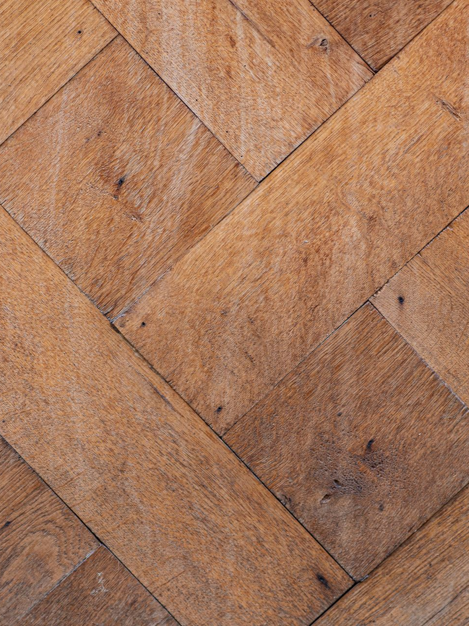 Un long couloir de bureau avec un parquet en bois dur poli aux tons chauds.