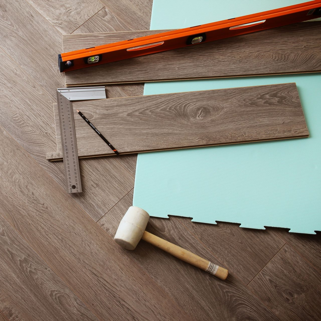 Vue de dessus d'un parquet clair présentant une éraflure sombre et incurvée sur sa surface.