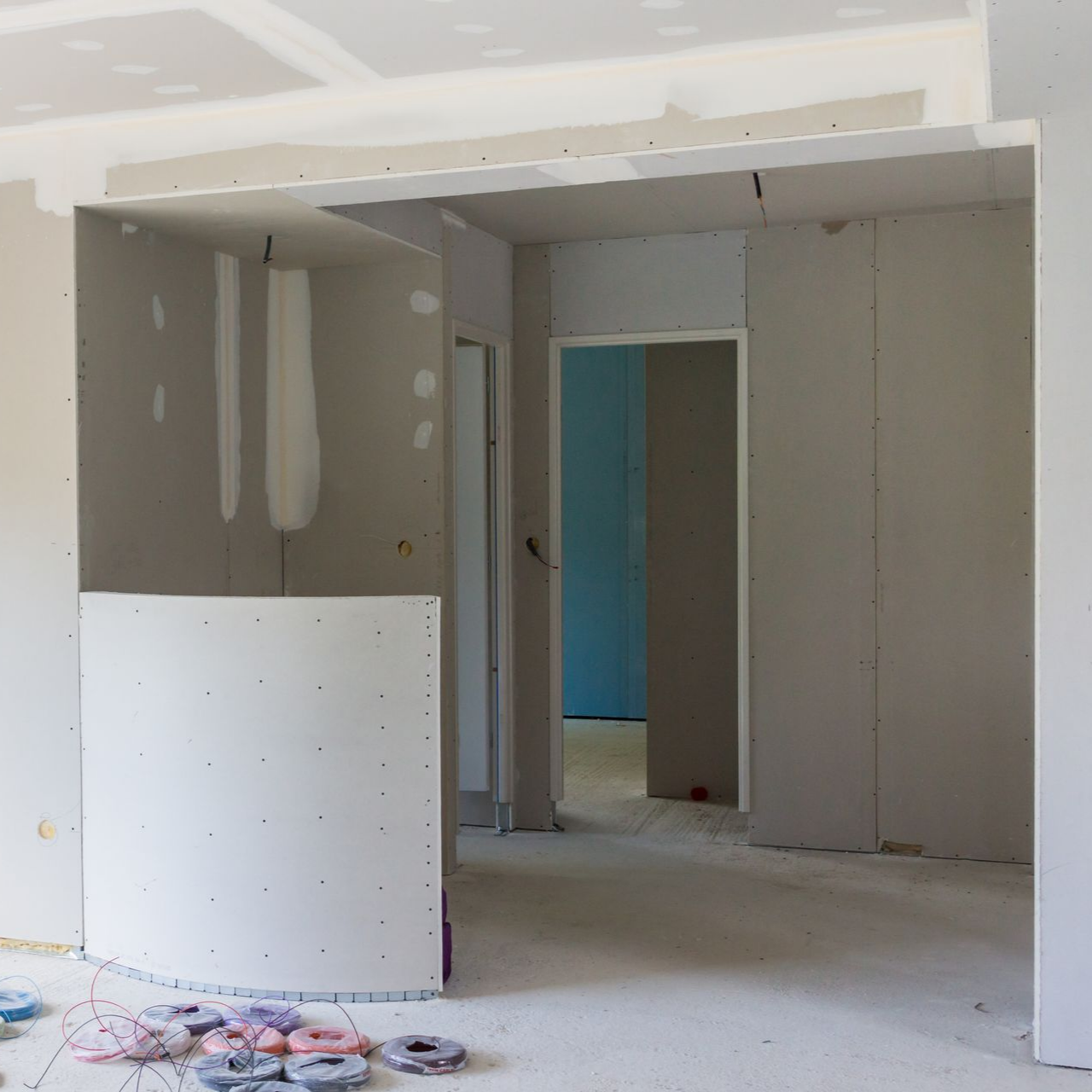 Une pièce en construction avec des cloisons sèches non finies et une paroi de séparation.