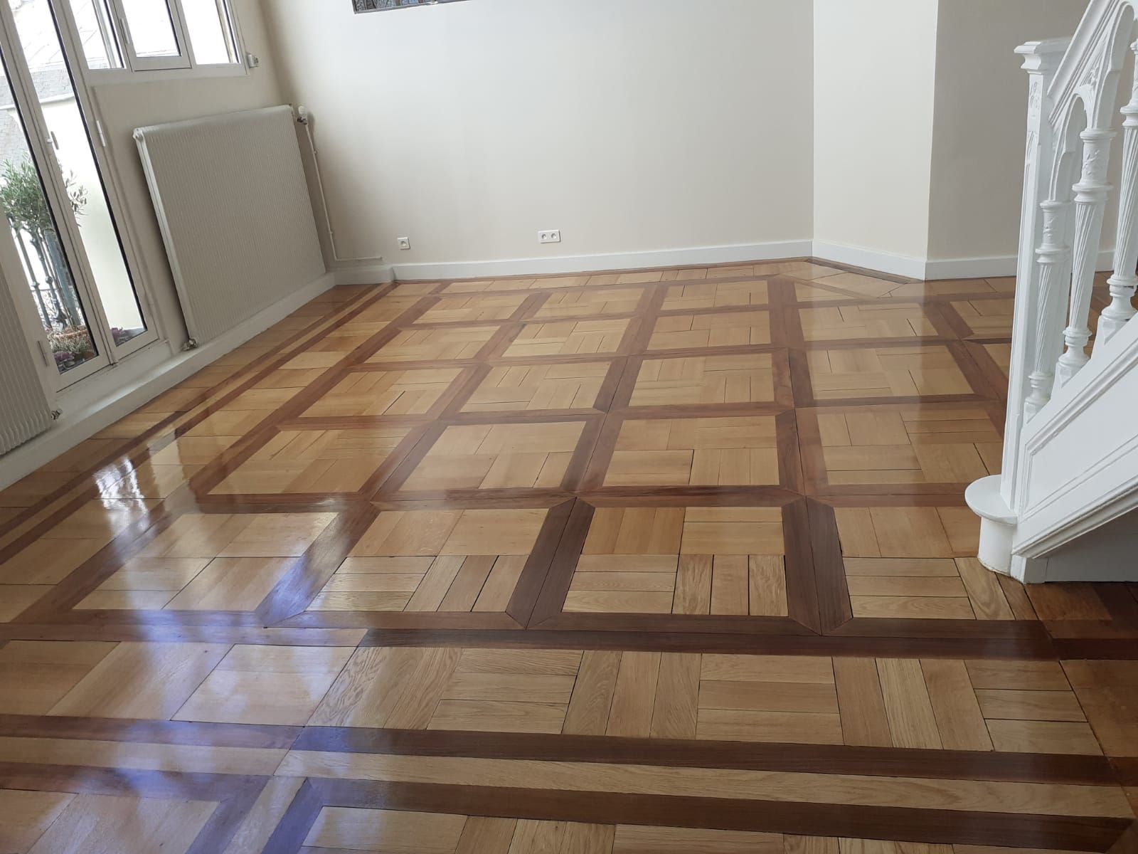 Parquet en bois clair et brillant, à motif géométrique.