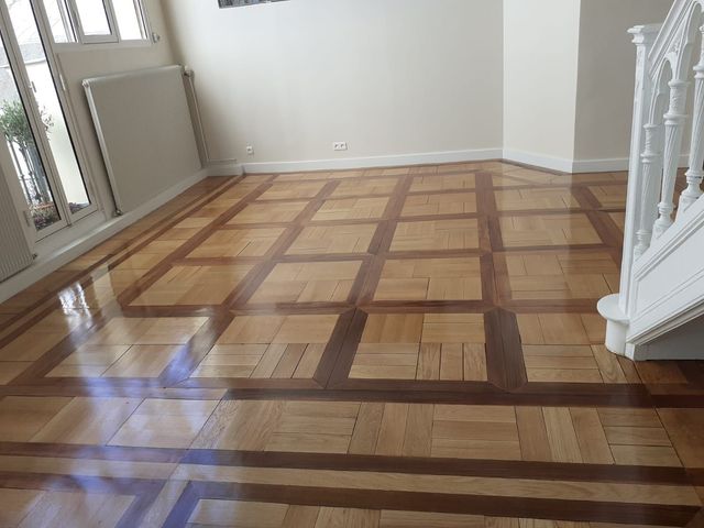 Parquet en bois clair et brillant, à motif géométrique.