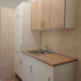 Eine Küche mit weißen Schränken, Holzarbeitsplatten und einer Spüle.