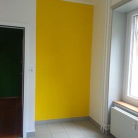 Ein Raum mit einer gelben Wand und einem Fenster.