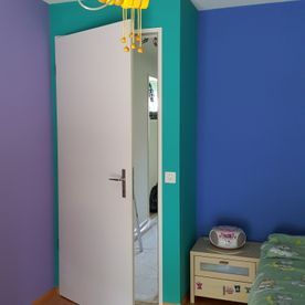 Ein Schlafzimmer mit blauen und violetten Wänden und einer weißen Tür.