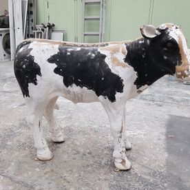 Eine schwarz-weiße Kuhstatue steht auf einem Betonboden.