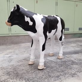 Eine schwarz-weiße Kuhstatue steht auf dem Boden
