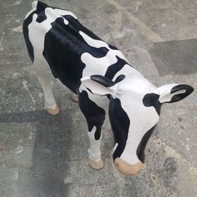 Eine schwarz-weiße Kuhstatue steht auf einem Betonboden.