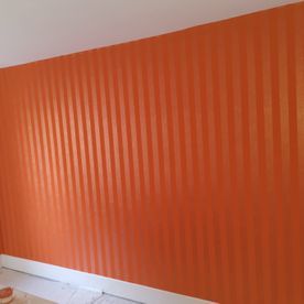 Ein Zimmer mit orange gestreifter Tapete an der Wand.