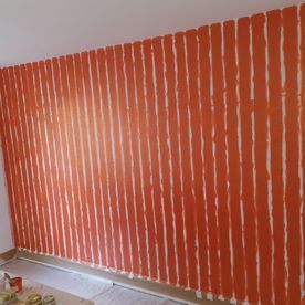 Eine Wand wird mit orangefarbenen und weißen Streifen bemalt.