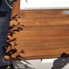 Ein Holztisch mit dem Schatten einer Pflanze darauf.