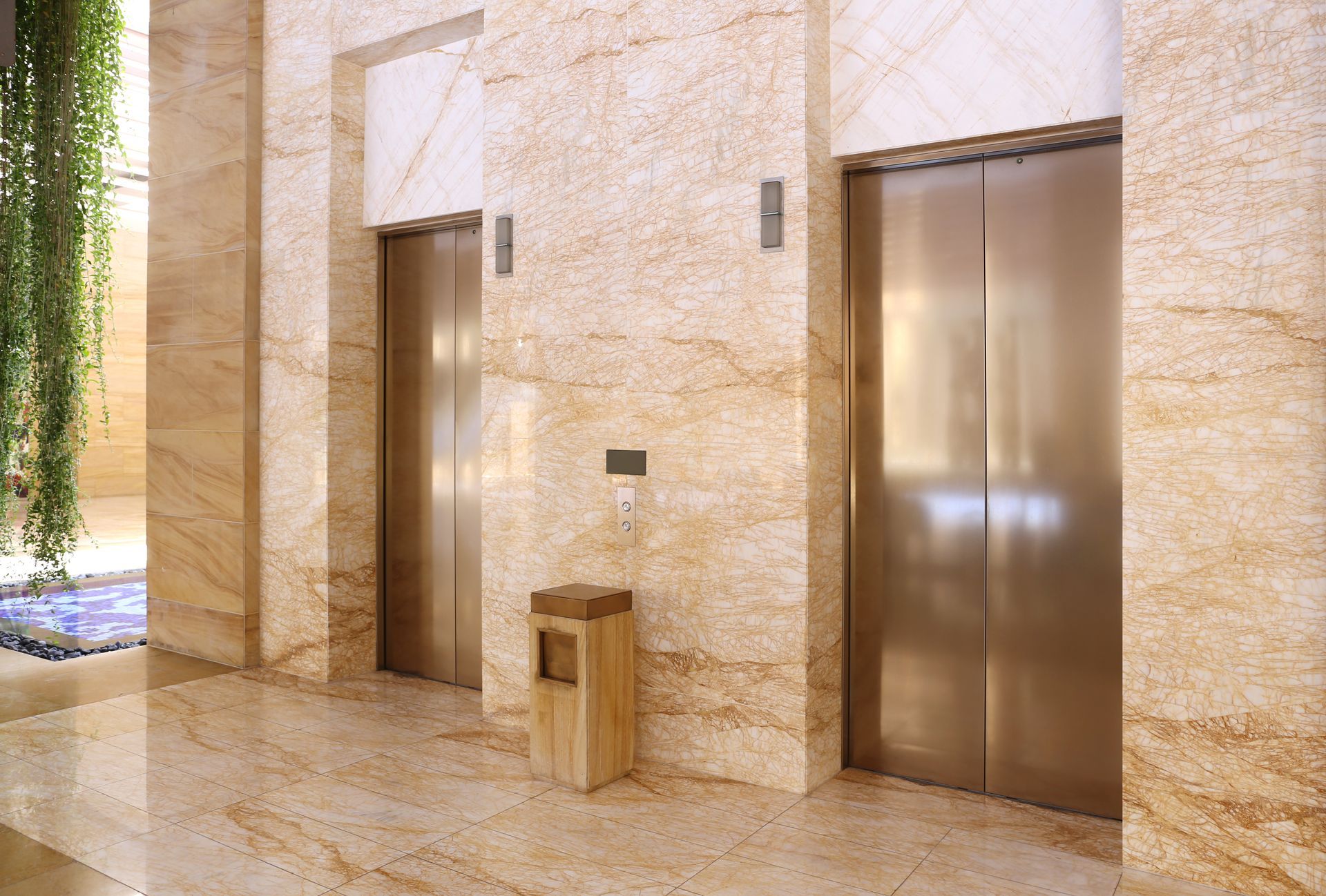 Hall d'entrée moderne en marbre avec deux portes d'ascenseur en acier inoxydable et un tabouret en bois au centre.