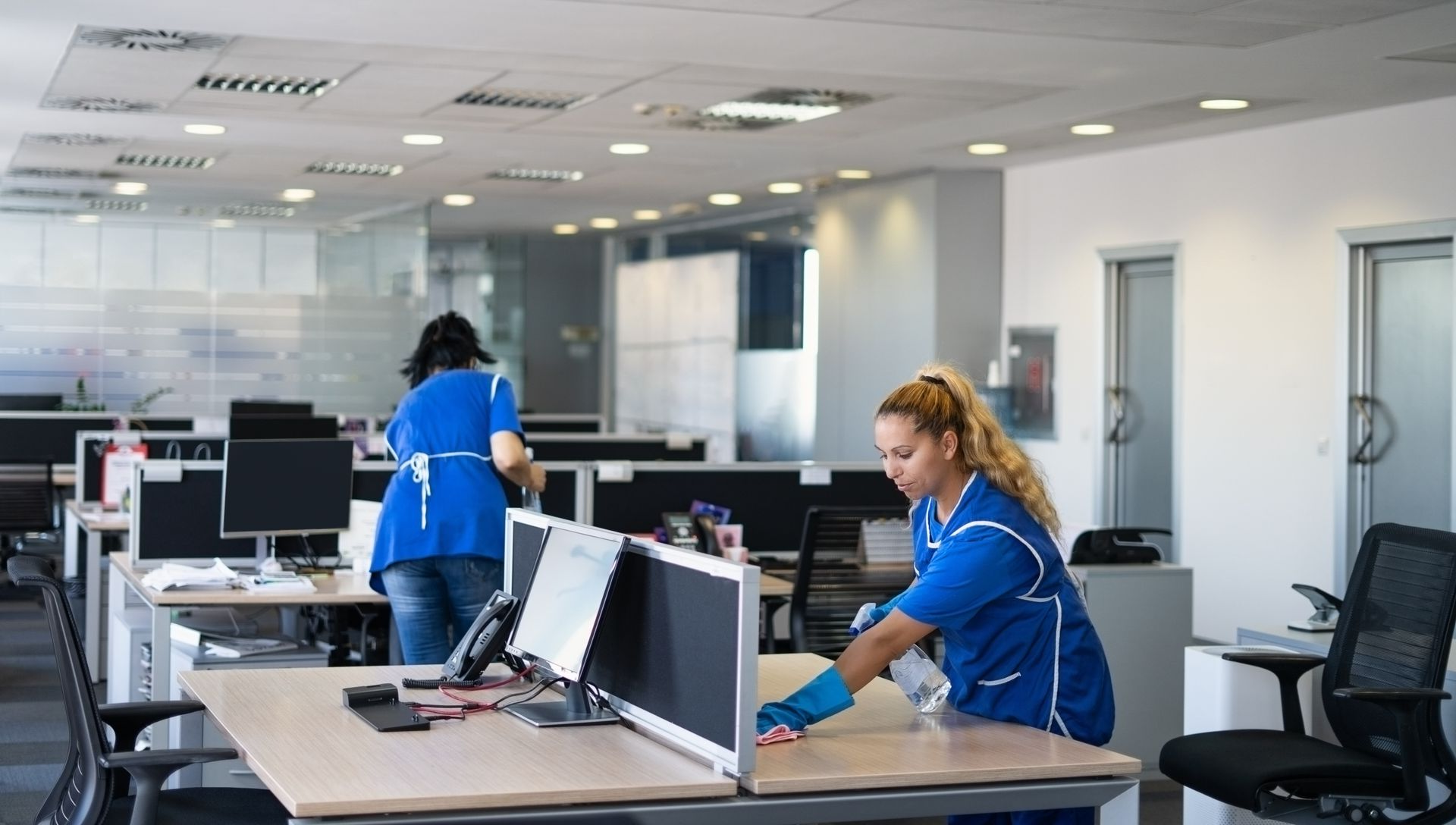 Deux femmes en train de nettoyer un bureau dans un bâtiment d'entreprise.