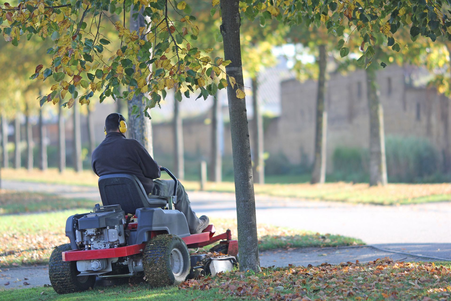 Un homme conduisant un tracteur-tondeuse et réalisant la tonte d'un jardin