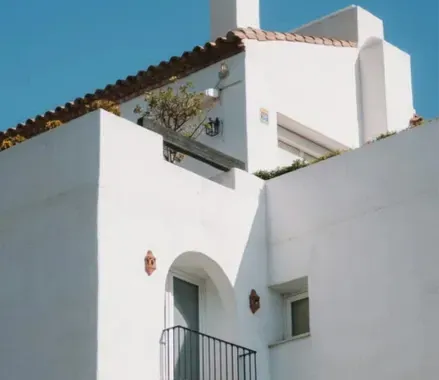 Un edificio blanco con balcón y chimenea pintado de blanco en sevilla