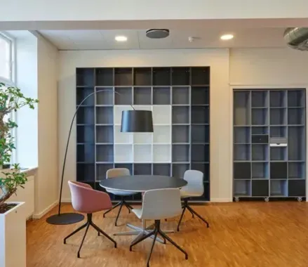 Una oficina con una mesa y sillas y una lámpara.