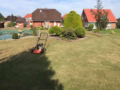 Ein Rasenmäher schneidet das Gras vor einem Haus