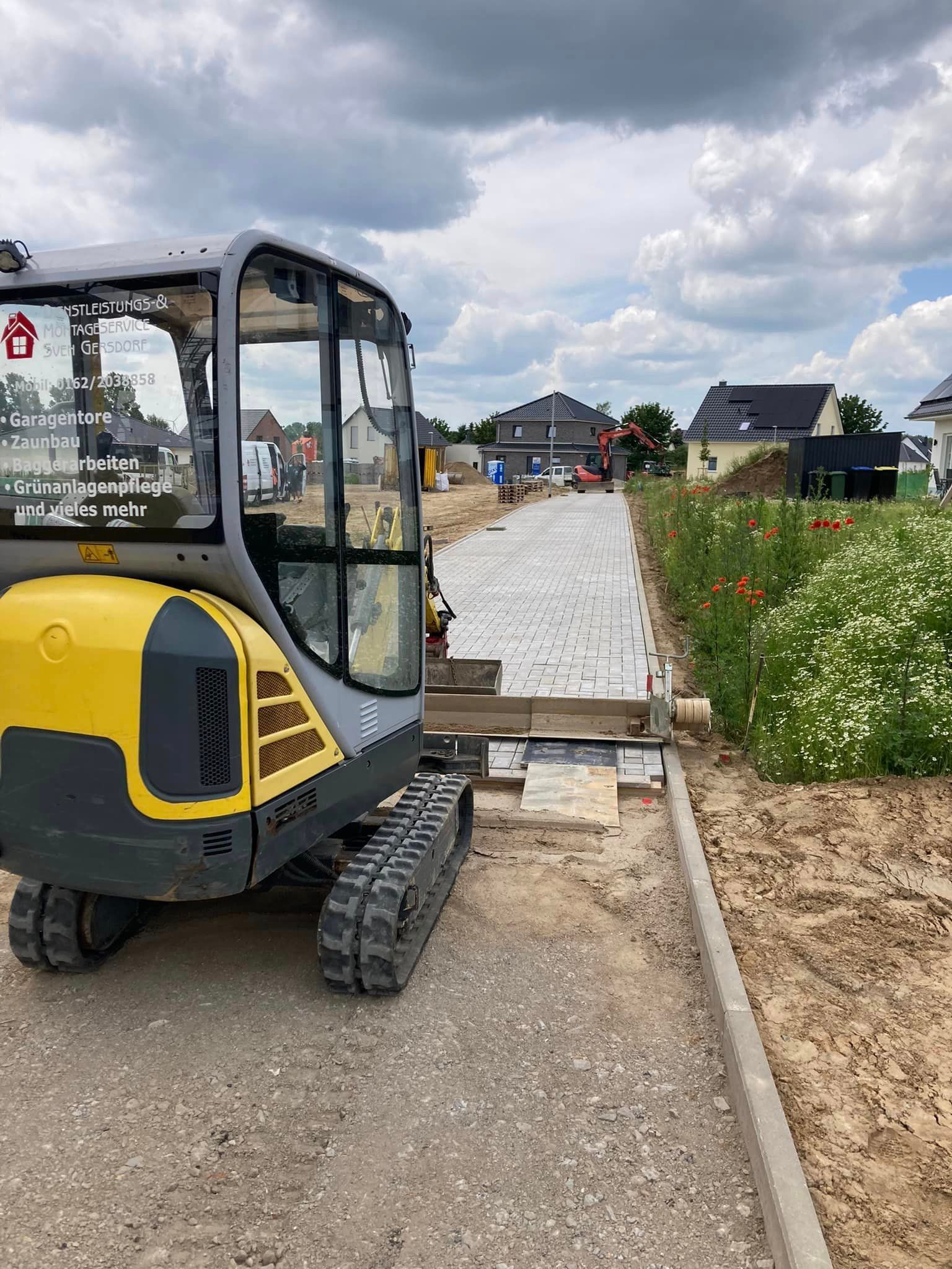 Ein gelb-grauer Bagger steht am Straßenrand.