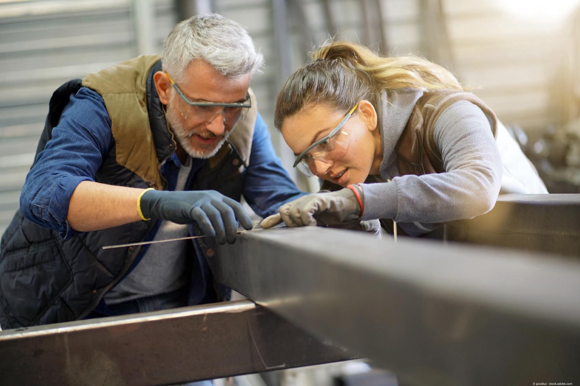 Metallarbeiter mit Lehrling in der Werkstatt Metallarbeiter mit Lehrling in der Werkstatt