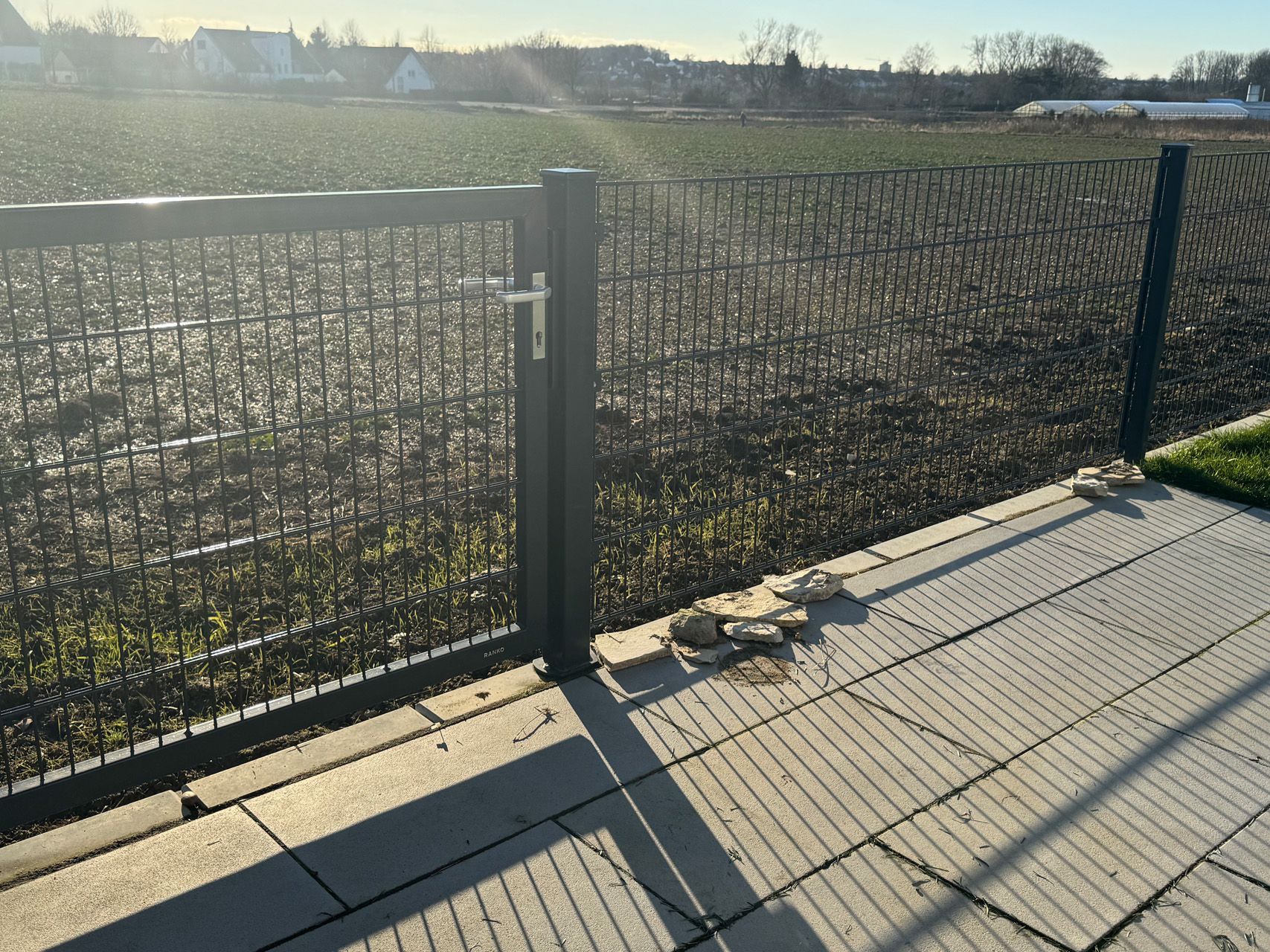 Ein Zaun mit einer Tür und einem Feld im Hintergrund