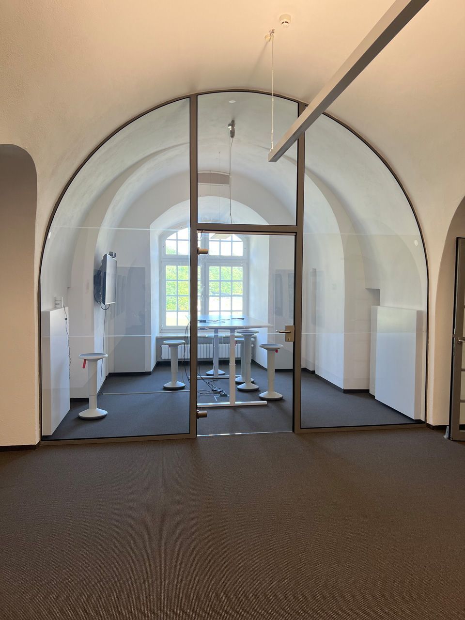 Ein Raum mit gewölbten Decken und einer Glastür